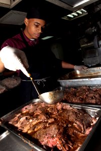 US Navy 110403-N-QP268-014 Culinary Specialist Seaman Recruit Bryan Pearson prepares two pans of sliced roast beef for the enlisted crew aboard USS