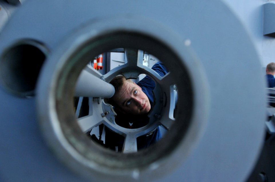 US Navy 110403-N-NL541-032 Gunner's Mate 1st Class Jeremy Pilkenton conducts a visual inspection of an MK 38 25 mm mounted gun to ensure proper lub