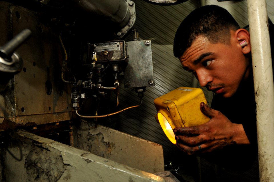 US Navy 110406-N-NL541-091 ngineman 2nd Class Justin Davila, assigned to the guided-missile frigate USS Boone (FFG 28), uses a flashlight to inspec