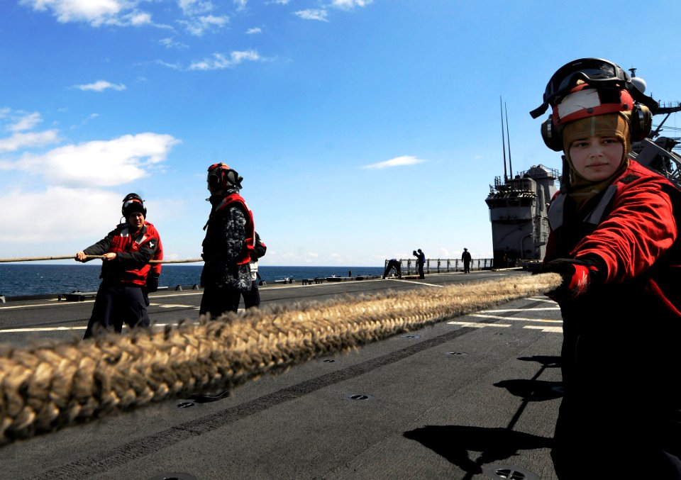 US Navy 110404-N-5716H-374 Culinary Specialist Seaman Apprentice Christina Baez positions safety nets around the flight deck of the amphibious tran