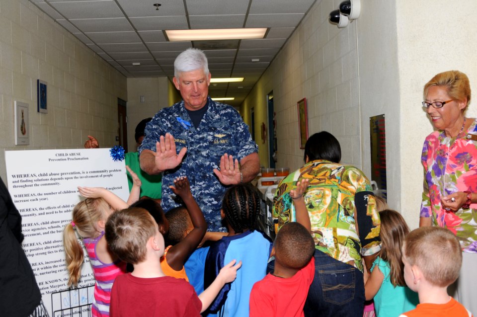 US Navy 110404-N-DD445-003 Capt. Douglas F. Cochrane, commanding officer of Naval Station Mayport, high-fives children after signing