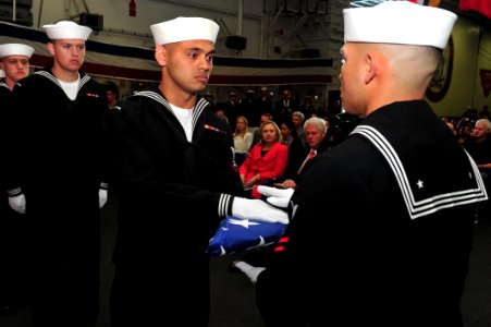US Navy 110401-N-KD852-536 Culinary Specialist 3rd Class Phillip Cotoio passes the national ensign to Logistics Specialist 2nd Class Marcusallen Bu
