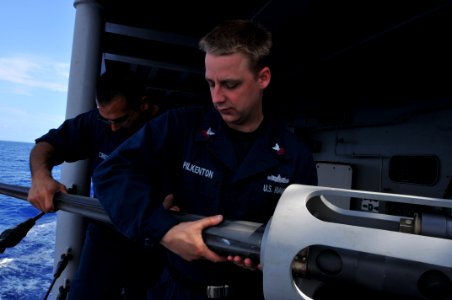 US Navy 110403-N-NL541-005 Gunner's Mate 1st Class Enrique Cruz and Gunner's Mate 1st Class Jeremy Pilkenton remove the barrel from an MK 38 25 mm