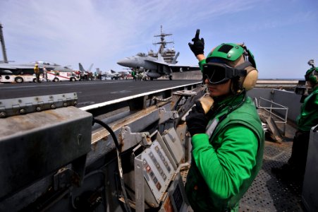 US Navy 110404-N-0569K-151 Aviation Boatswain's Mate (Equipment) 2nd Class Leonardo Valdez-Fonseca signals to a shooter as an F-A-18E Super Hornet