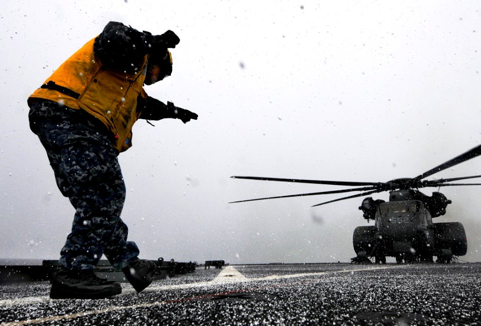US Navy 110404-N-5716H-387 Boatswain's Mate Seaman Janmark Rivera signals to an MH-53E Sea Dragon helicopter aboard USS Tortuga (LSD 46)