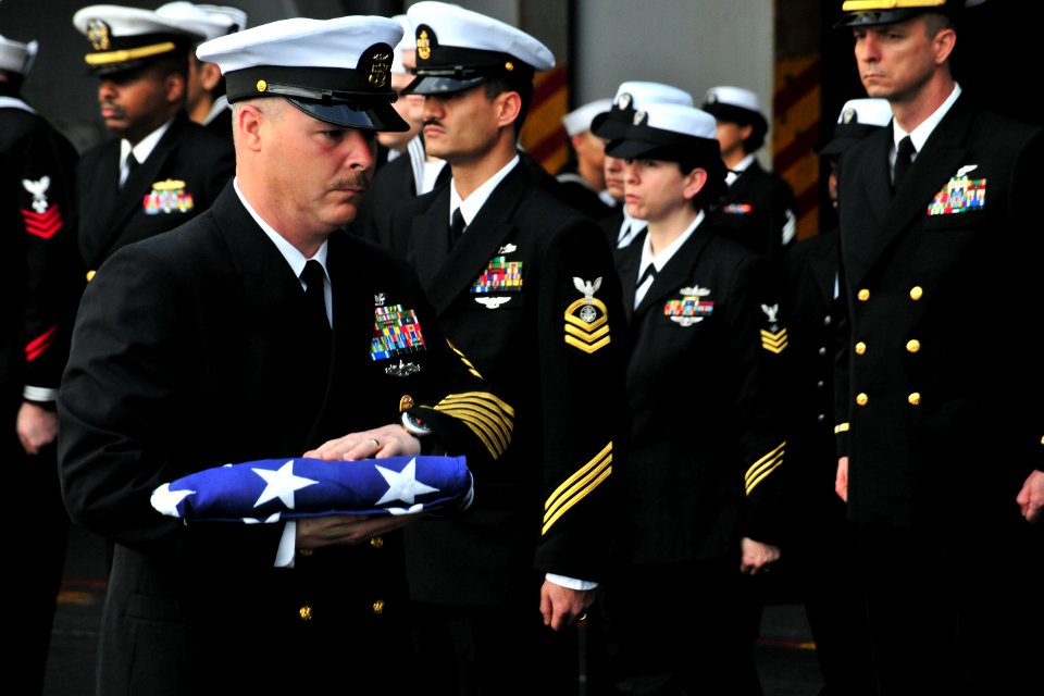 US Navy 110409-N-0074G-070 Master Chief Keith G. Oxley carries a flag during a burial at sea aboard USS Enterprise (CVN 65)