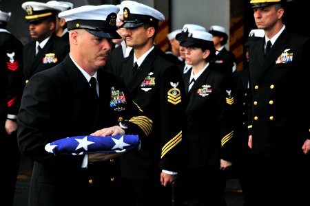 US Navy 110409-N-0074G-070 Master Chief Keith G. Oxley carries a flag during a burial at sea aboard USS Enterprise (CVN 65)