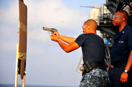 US Navy 110406-N-ZS026-059 Aviation Ordnanceman 3rd Class Rayjuan Horton fires a 9mm pistol from behind cover during a small arms practical weapons photo