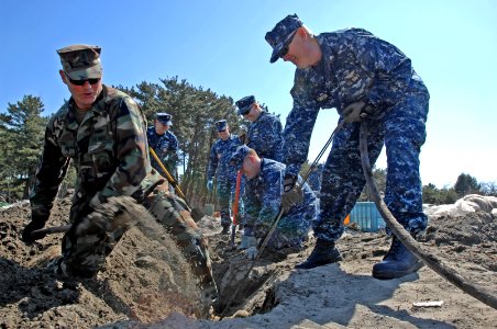 US Navy 110406-N-OM503-067 Chief Construction Mechanic Michael Robb shovels away layers of sediment while Chief Naval Air Crewman (Operational Leve