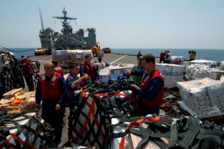 US Navy 110409-N-RC734-287 Sailors and Marines remove cargo nets from pallets of supplies aboard the amphibious dock landing ship USS Comstock (LSD