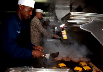 US Navy 110406-N-QP268-107 Culinary Specialist 1st Class Victor Mitchell and Sgt. Evan Westpfahl prepare grilled hamburgers for Sailors and Marines photo