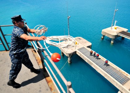 US Navy 110412-N-5538K-243 Seaman Recruit Michael A. Barbosa casts a mooring line as the forward-deployed amphibious assault ship USS Essex (LHD 2)