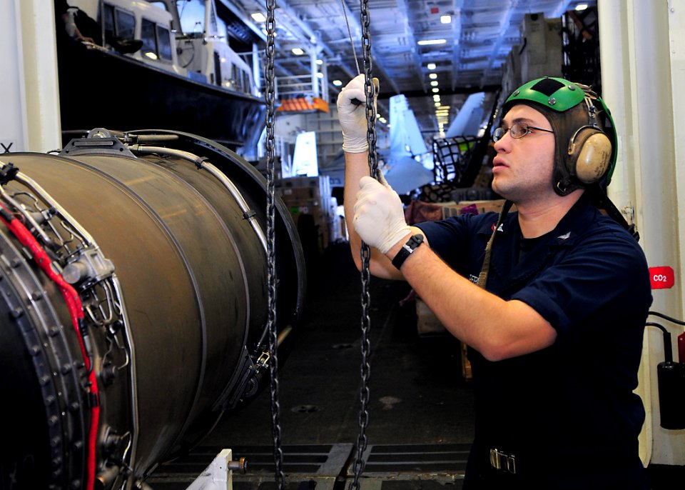US Navy 110407-N-DM338-101 Aviation Machinist's Mate 3rd Class Luis Perez, from West Palm Beach, Fla., hoists an engine from an F-A-18 Hornet in th