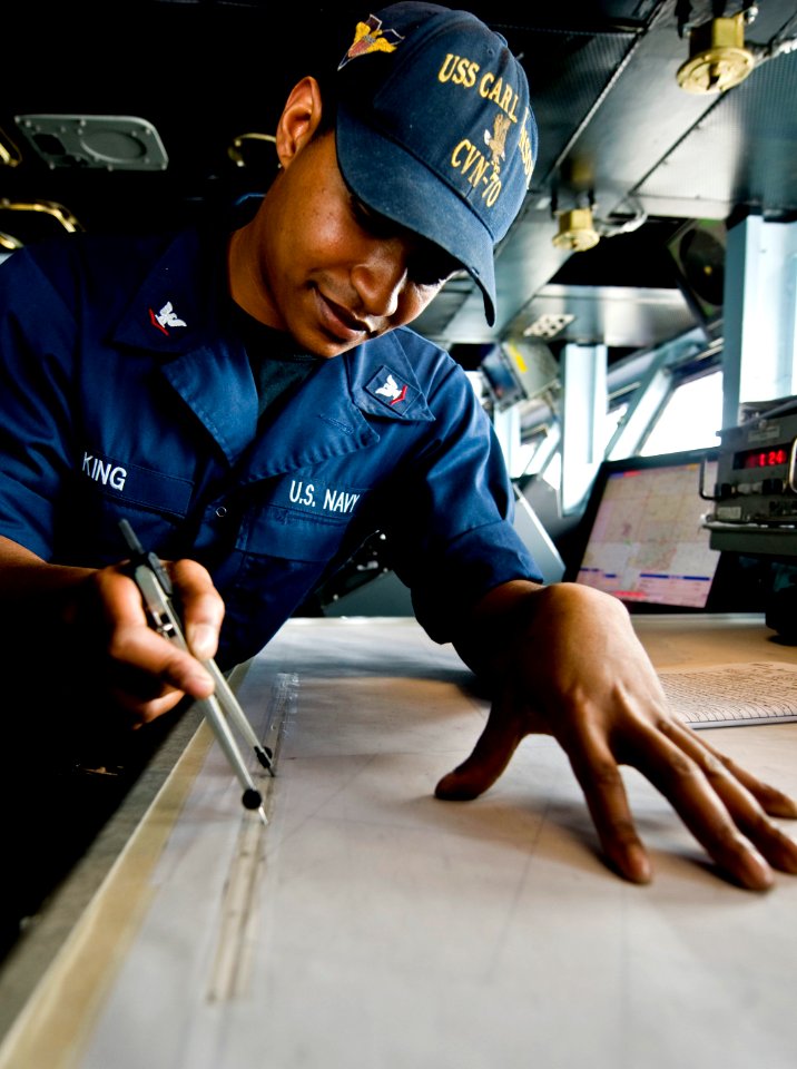 US Navy 110412-N-6320L-043 Quartermaster 3rd Class Eddie King plots navigation points on the ship's bridge