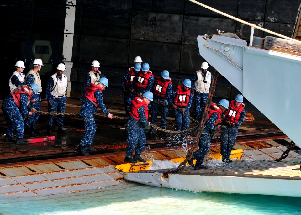 US Navy 110412-N-5538K-522 Sailors assigned to the forward-deployed amphibious assault ship USS Essex (LHD 2) carry chains onto a landing craft uti