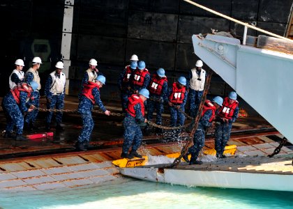 US Navy 110412-N-5538K-522 Sailors assigned to the forward-deployed amphibious assault ship USS Essex (LHD 2) carry chains onto a landing craft uti