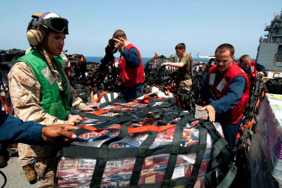 US Navy 110409-N-RC734-275 Sailors and Marines remove cargo nets from pallets of supplies aboard the amphibious dock landing ship USS Comstock (LSD