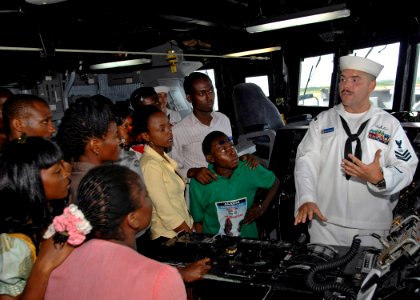 US Navy 110411-N-HI707-340 Fire Controlman 1st Class Philip Soltwedel explains the function of the ship's helm to a tour group from Echoes From Aje