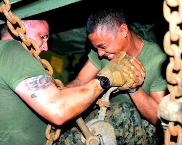 US Navy 110412-F-HS649-046 Marines tighten down chains on a truck in the well deck of the amphibious transport dock ship USS Cleveland (LPD 7) photo
