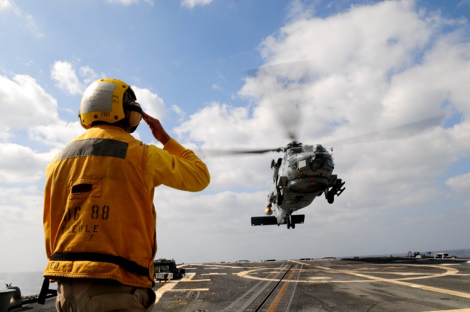US Navy 110412-N-SG869-110 Personnel Specialist 2nd Class Edwin Barrientos signals for an SH-60B Sea Hawk helicopter to land aboard the guided-miss