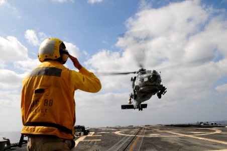 US Navy 110412-N-SG869-110 Personnel Specialist 2nd Class Edwin Barrientos signals for an SH-60B Sea Hawk helicopter to land aboard the guided-miss
