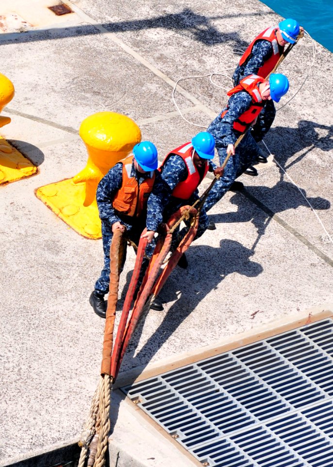 US Navy 110412-N-5538K-208 Sailors assigned to White Beach Naval Facility heave mooring lines from the forward-deployed amphibious assault ship USS