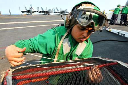 US Navy 110415-N-1004S-018 Aviation Machinist Mate 2nd Class Alfred sews together a tear in an engine turn screen aboard USS Ronald Reagan (CVN 76)