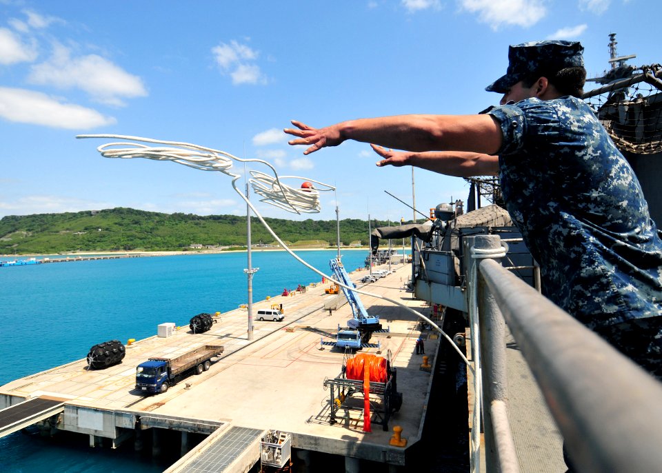 US Navy 110412-N-5538K-188 Seaman Recruit Michael A. Barbosa casts a mooring line as the forward-deployed amphibious assault ship USS Essex (LHD 2)