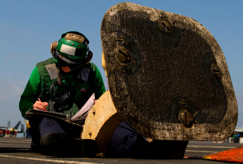 US Navy 110412-N-7488A-079 Aviation Boatswain's Mate 3rd Class George Pownall logs temperature and pressure numbers on the catapult No. 3 and 4 run
