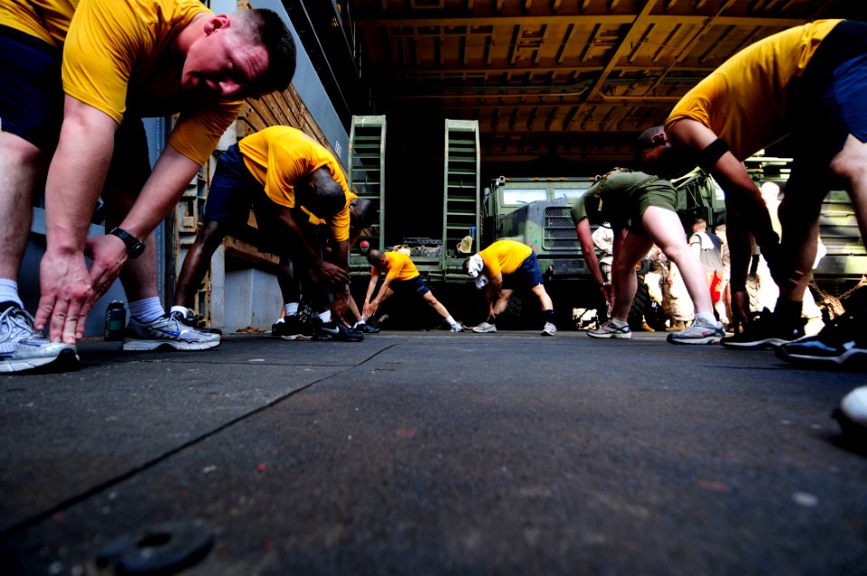 US Navy 110414-N-RC734-654 Sailors and Marines stretch during physical training aboard the amphibious dock landing ship USS Comstock (LSD 45)