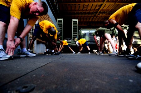 US Navy 110414-N-RC734-654 Sailors and Marines stretch during physical training aboard the amphibious dock landing ship USS Comstock (LSD 45)