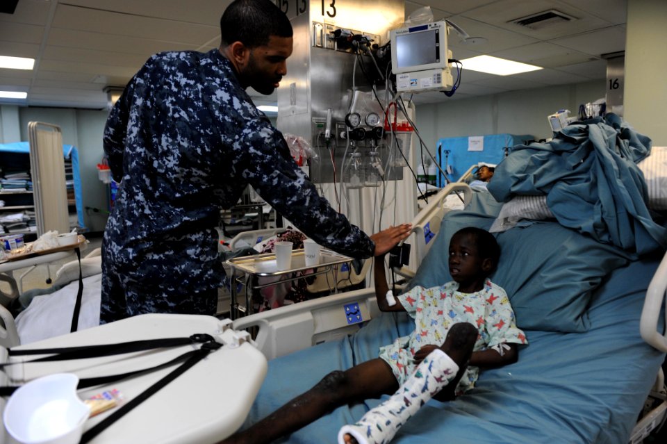 US Navy 110417-F-NJ219-320 Hospital Corpsman 3rd Class Lamonte Hammond hi-fives a Jamaican boy after his physical therapy treatment aboard USNS Com