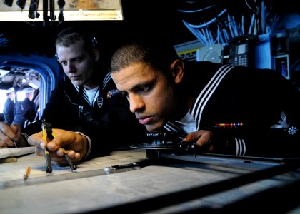US Navy 110414-N-RU841-040 Quartermaster 3rd Class Elvis Gomez, right, checks a navigation chart while Quartermaster 2nd Class Kevin Bell makes a l