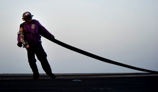 US Navy 110418-N-DR144-456 A Sailor drags a fuel hose to an aircraft on the flight deck