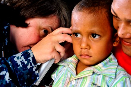 US Navy 110417-O-XX000-004 Cmdr. Christine Johnson, left, examines a boy's ear at a remote Pacific Partnership 2011 medical humanitarian assistance photo