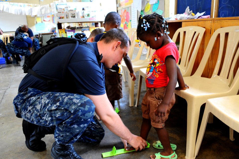 US Navy 110421-F-CF975-036 Aviation Ordnanceman 3rd Class Robert Noonan, from South Boston, N.Y., fits a student for shoes during a Continuing Prom