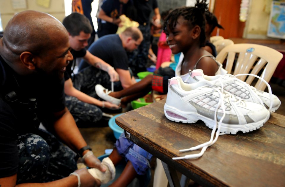 US Navy 110421-F-ET173-131 Hospital Corpsman 2nd Class Fletcher Crawley, from Crewe, Va., fits a girl for a pair of shoes during a Continuing Promi