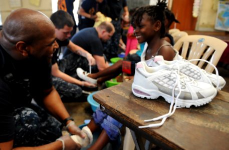 US Navy 110421-F-ET173-131 Hospital Corpsman 2nd Class Fletcher Crawley, from Crewe, Va., fits a girl for a pair of shoes during a Continuing Promi photo
