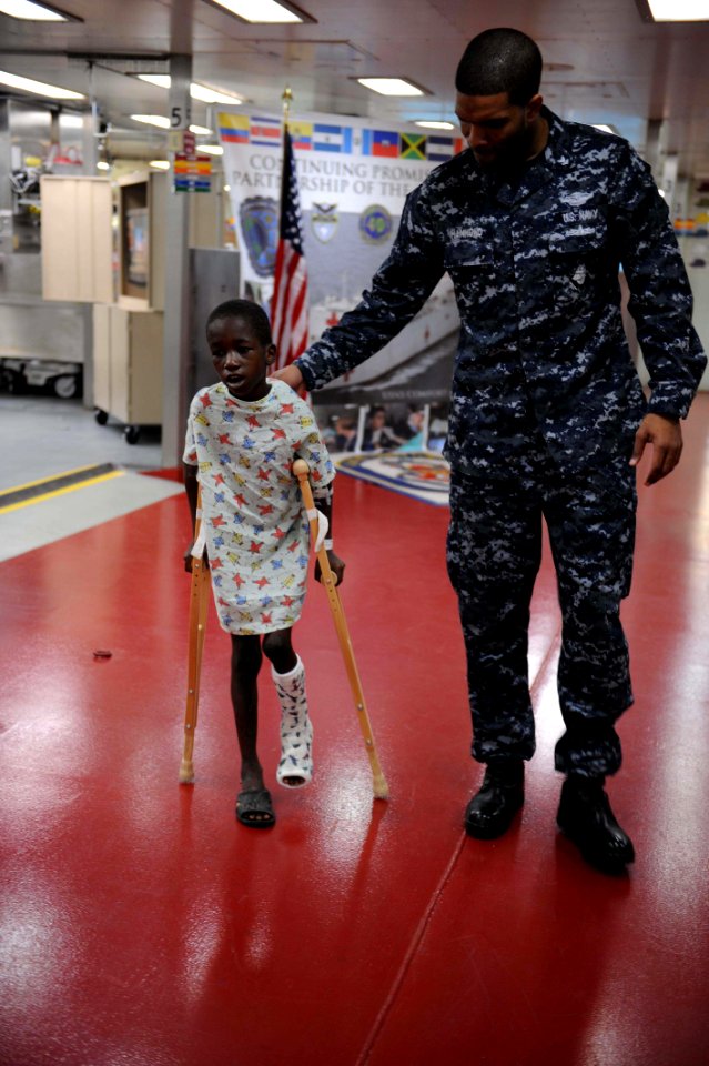 US Navy 110417-F-NJ219-278 Hospital Corpsman 3rd Class Lamonte Hammond steadies a Jamaican boy learning to use his crutches after undergoing surger