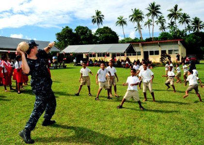 US Navy 110418-F-HS649-291 Musician 3rd Class Stephen Weninger throws a rugby ball while playing with Tongan children before a ribbon cutting cerem