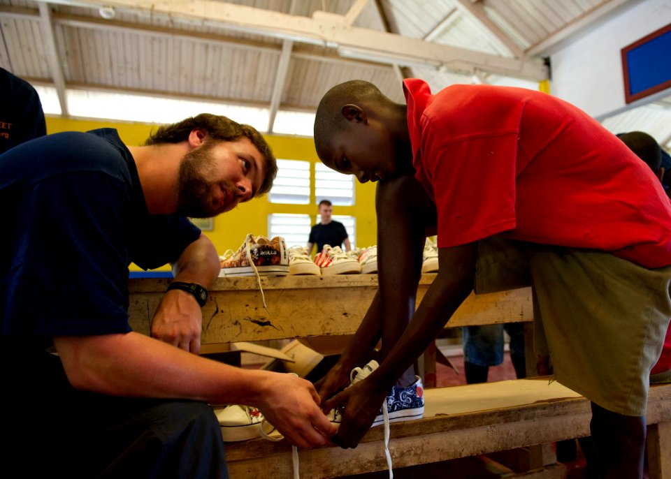 US Navy 110420-N-RM525-601 Harrison Hanvey fits a student with a new pair of shoes during a Continuing Promise 2011 community service project