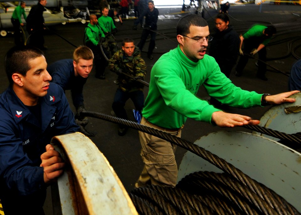 US Navy 110422-N-1004S-222 Sailors flake off arresting gear wires in the hangar bay of the aircraft carrier USS Ronald Reagan (CVN 76)