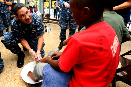 US Navy 110421-F-CF975-233 Capt. Brian Nickerson, mission commander of Continuing Promise 2011, washes the feet of a Harbor View Primary School stu photo