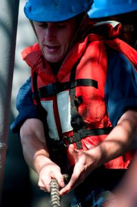 US Navy 110419-N-RC734-122 Fire Controlman 3rd Class Derick Taylor heaves a line aboard the amphibious dock landing ship USS Comstock (LSD 45)
