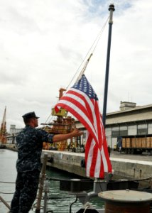 US Navy 110421-N-NL541-076 Fire Controlman 2nd Class Jordon Babin lowers the national ensign on the fantail of the guided-missile frigate USS Thach