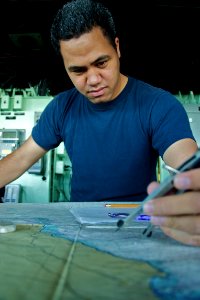 US Navy 110425-N-ZC343-680 Quartermaster 3rd Class Jeremiah Pulu practices plotting navigation routes on the bridge of USS Bonhomme Richard (LHD 6)