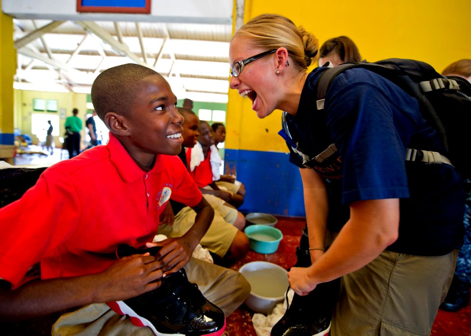 US Navy 110420-N-RM525-542 Kari Williams, Continuing Promise 2011 international program director for education, gives a new pair of shoes to a stud