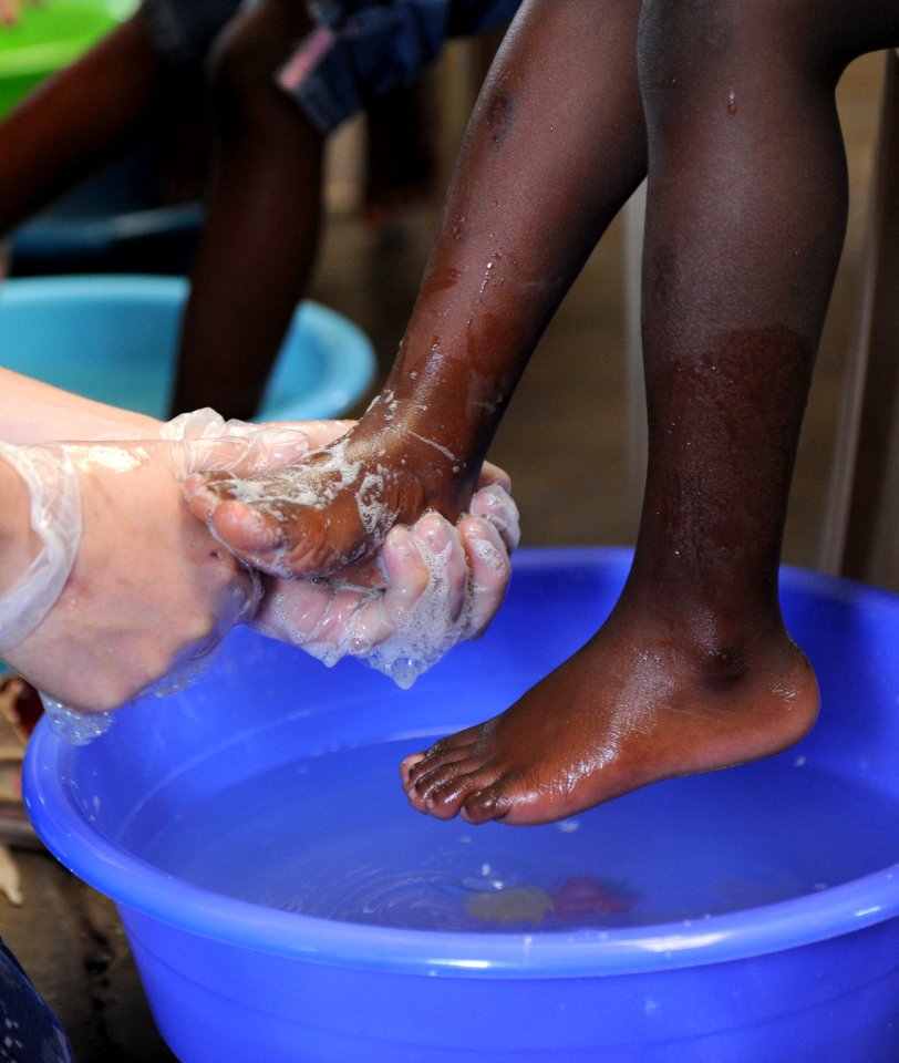 US Navy 110421-F-ET173-062 A Sailor washes a child's feet before giving him a new pair of shoes during a Continuing Promise shoe give-away photo