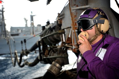 US Navy 110421-N-0569K-008 Aviation Boatswain's Mate (Fuels) Airman Michael A. Genera uses a sound-powered telephone to communicate with the fuels