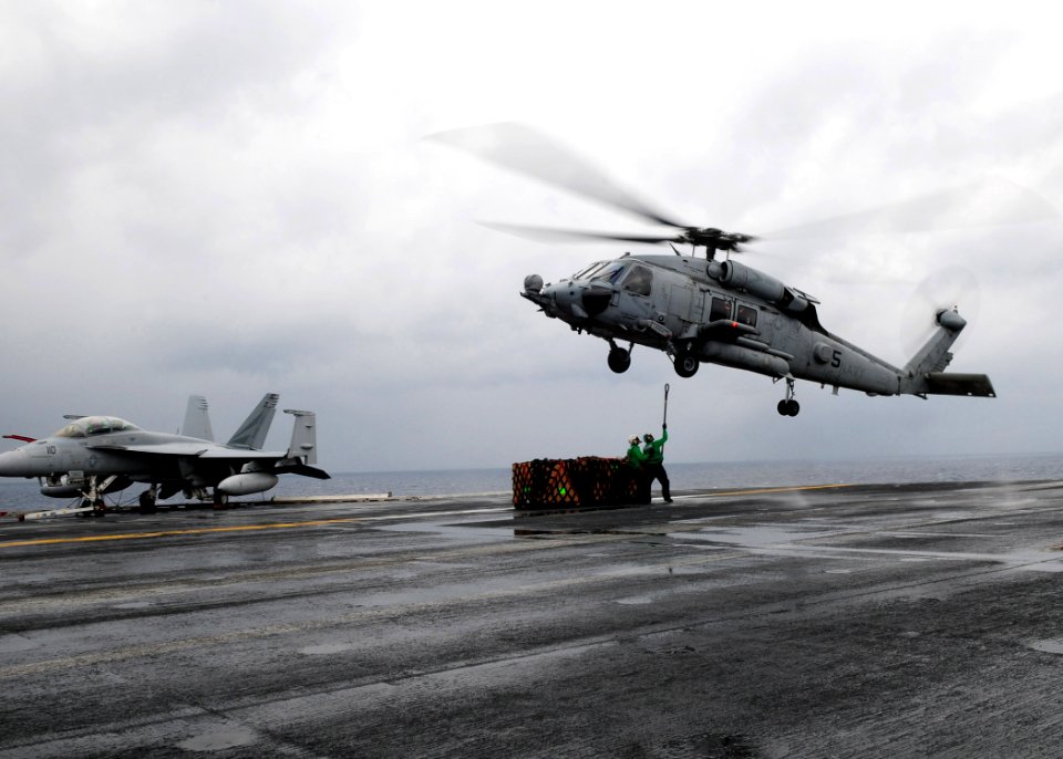 US Navy 110423-N-SG869-047 Logistics Specialist Seaman Immanuel Carter and Logistics Specialist 1st Class Kristopher Forest hook a load onto an SH